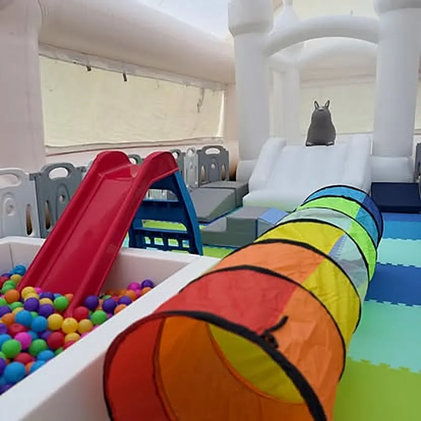 Túnel de gateo arcoíris, tobogán rojo y piscina de pelotas de colores