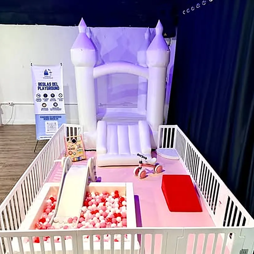 Castillo inflable lila iluminado de noche con piscina de pelotas rosa