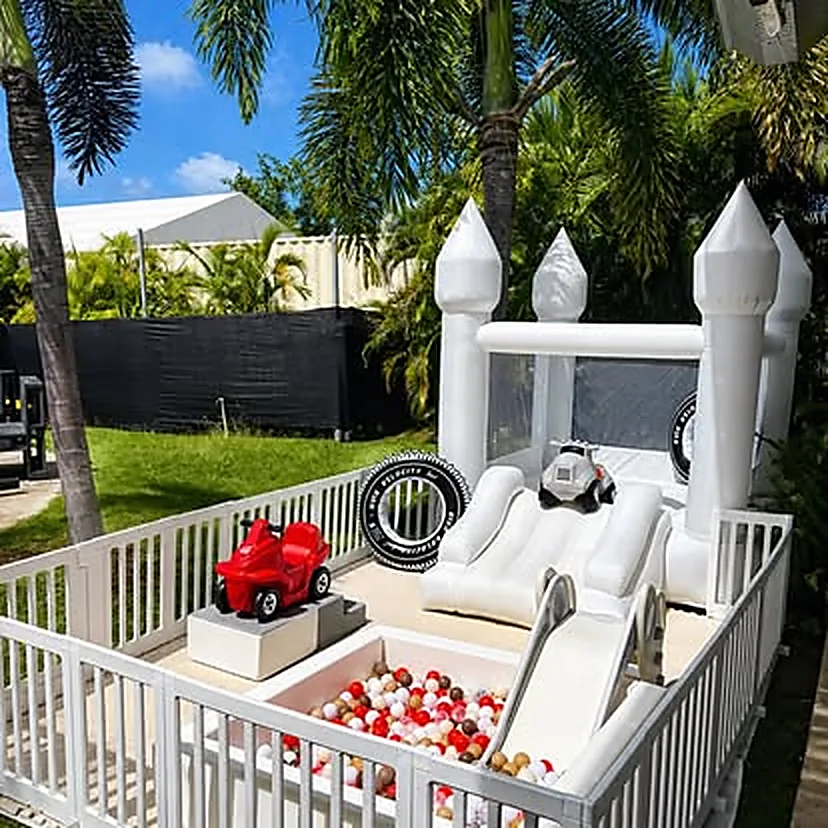 Castillo blanco con carrito rojo y piscina de pelotas roja y blanca en el patio