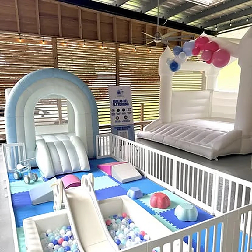 Bounce house blanco y arco celeste montados juntos en un salón techado